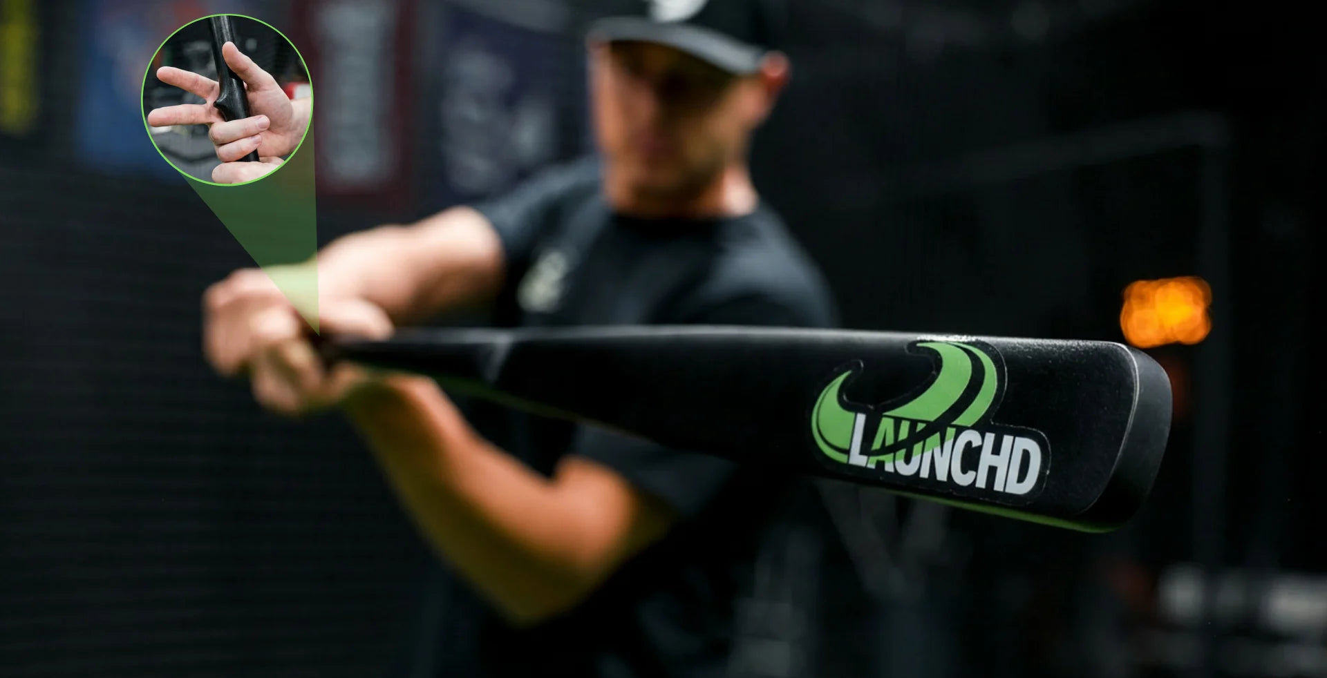 Person holding a black baseball bat with 'Launchd' logo, blurred background