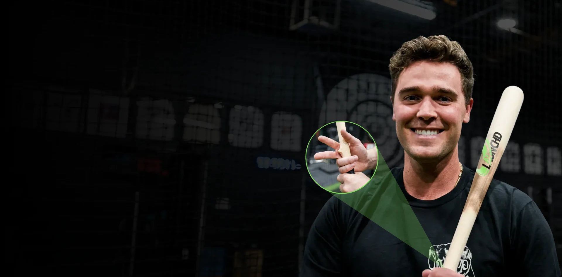 Man holding a baseball bat with a close-up of his hand on a dark background