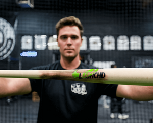Person holding a baseball bat with a visible brand logo in an indoor setting