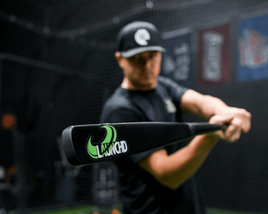 Person holding a baseball bat in a batting cage with a black and green bat