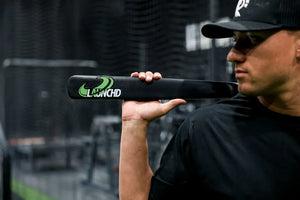 Person holding a black bat with 'Launchd' branding in an outdoor setting