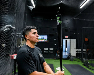 Person holding a baseball bat in a batting cage